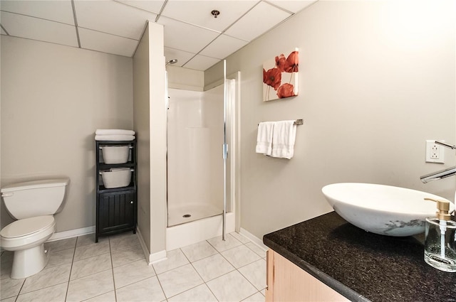 bathroom featuring walk in shower, toilet, vanity, tile patterned flooring, and a drop ceiling