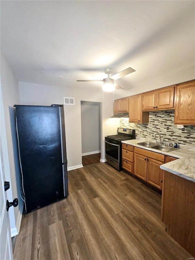 kitchen with sink, appliances with stainless steel finishes, dark hardwood / wood-style floors, ceiling fan, and decorative backsplash