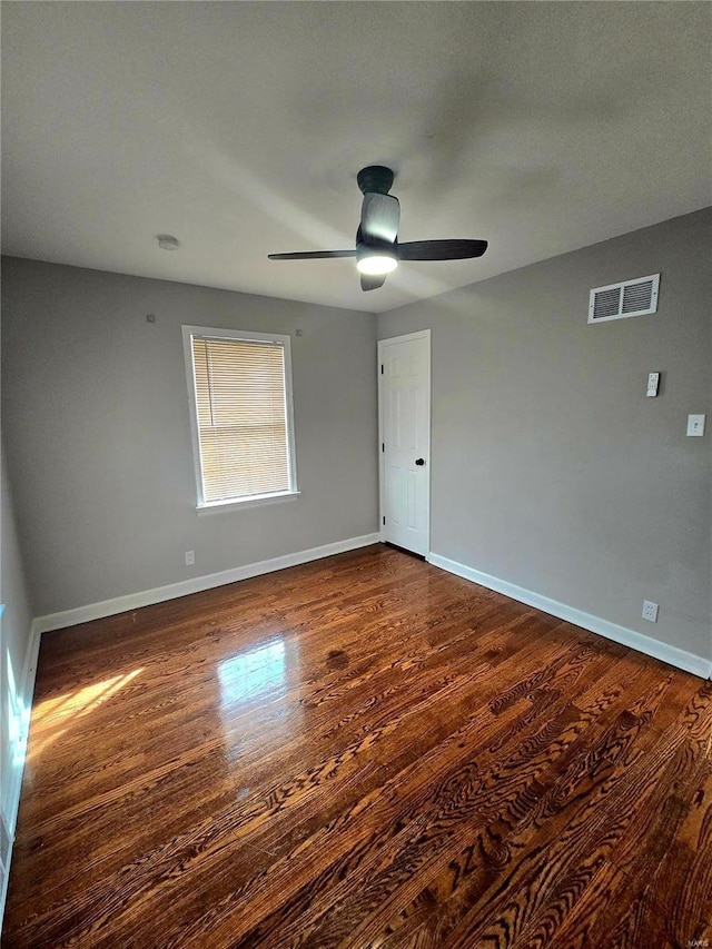 empty room with ceiling fan and dark hardwood / wood-style flooring