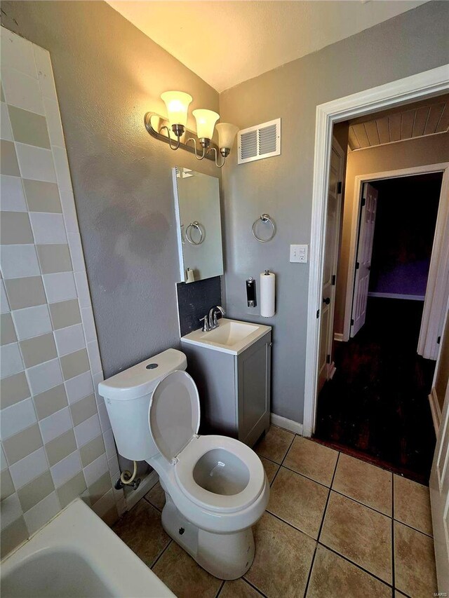 bathroom with a chandelier, tile patterned flooring, vanity, a washtub, and toilet