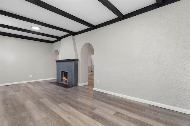 unfurnished living room featuring hardwood / wood-style flooring and beam ceiling