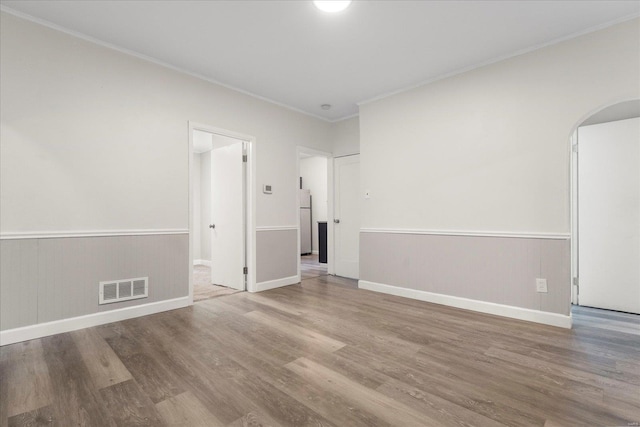 spare room featuring hardwood / wood-style flooring and ornamental molding