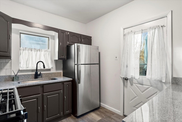 kitchen featuring sink, stainless steel fridge, dark hardwood / wood-style floors, dark brown cabinetry, and gas range oven