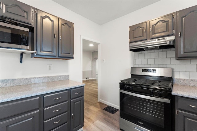 kitchen featuring stainless steel appliances, decorative backsplash, and light hardwood / wood-style flooring