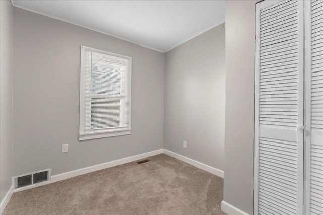 carpeted spare room featuring crown molding