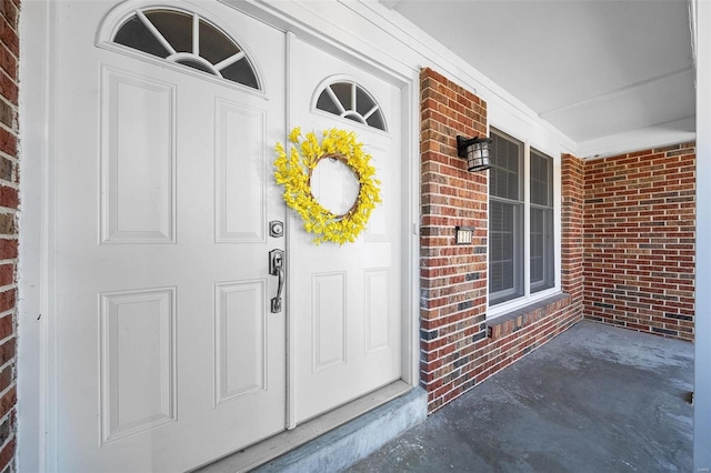 view of exterior entry featuring brick siding and covered porch