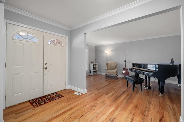 foyer featuring light wood finished floors, baseboards, and ornamental molding