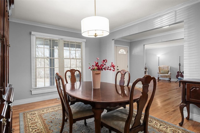 dining space with light wood-style flooring, crown molding, and baseboards