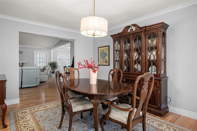 dining room with baseboards, light wood-style floors, and ornamental molding