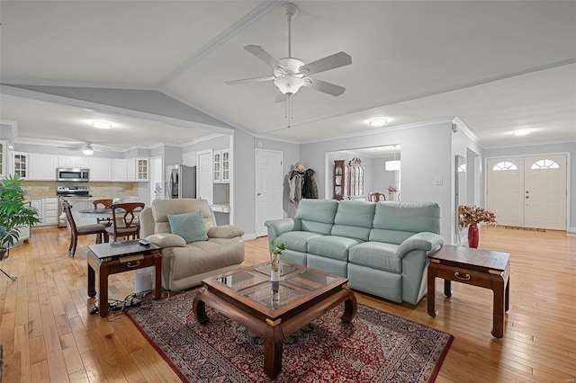 living area with lofted ceiling, ornamental molding, and light wood finished floors