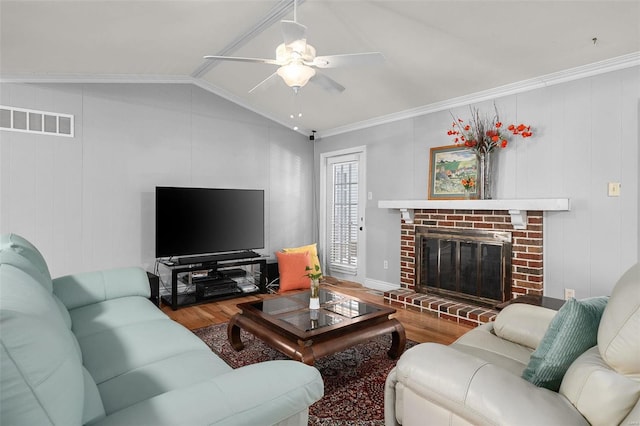 living area featuring vaulted ceiling, crown molding, wood finished floors, and visible vents