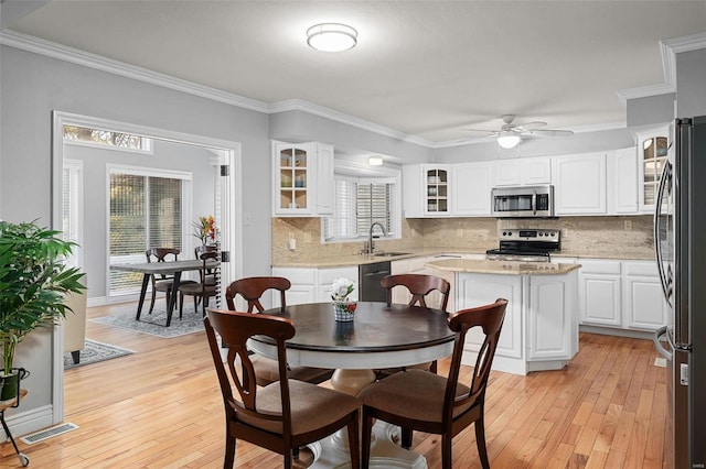 dining room with visible vents, light wood-style floors, and ornamental molding