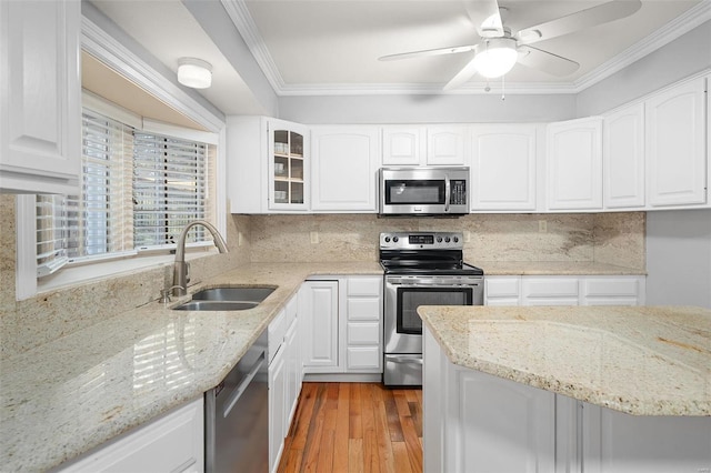 kitchen with a sink, backsplash, stainless steel appliances, crown molding, and glass insert cabinets