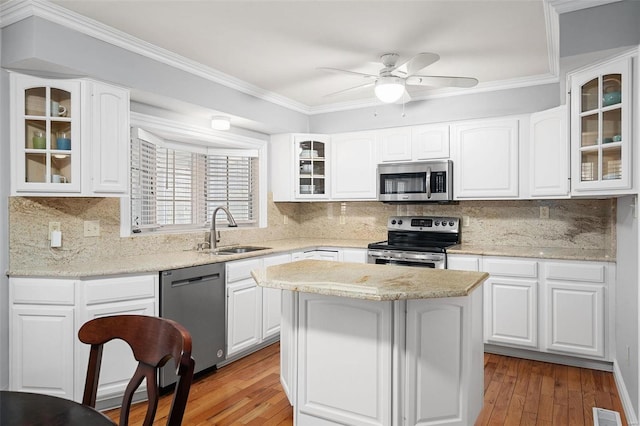 kitchen featuring a sink, stainless steel appliances, light wood-type flooring, and crown molding