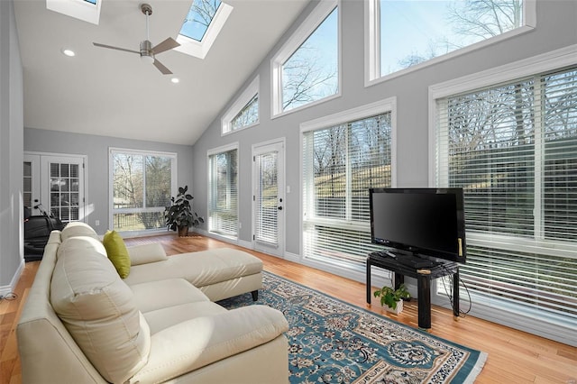 living room featuring high vaulted ceiling, wood finished floors, recessed lighting, a skylight, and ceiling fan