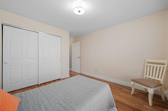 bedroom with wood finished floors, baseboards, and a closet