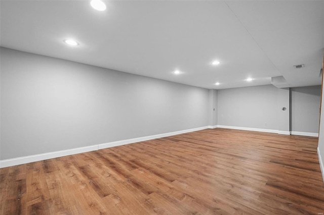 finished basement with recessed lighting, visible vents, baseboards, and wood finished floors