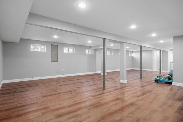 basement with electric panel, baseboards, light wood-style floors, and recessed lighting