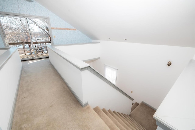 staircase with lofted ceiling, carpet flooring, and wallpapered walls