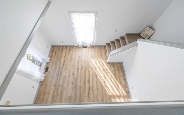 stairs featuring wood finished floors, a wealth of natural light, and visible vents