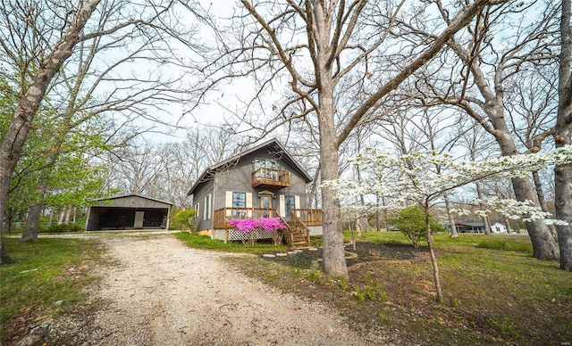 view of front facade featuring an outbuilding, a carport, a balcony, a deck, and dirt driveway