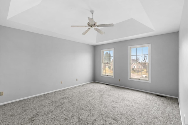 spare room featuring a tray ceiling, ceiling fan, and carpet flooring