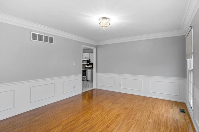 empty room with ornamental molding and light hardwood / wood-style floors