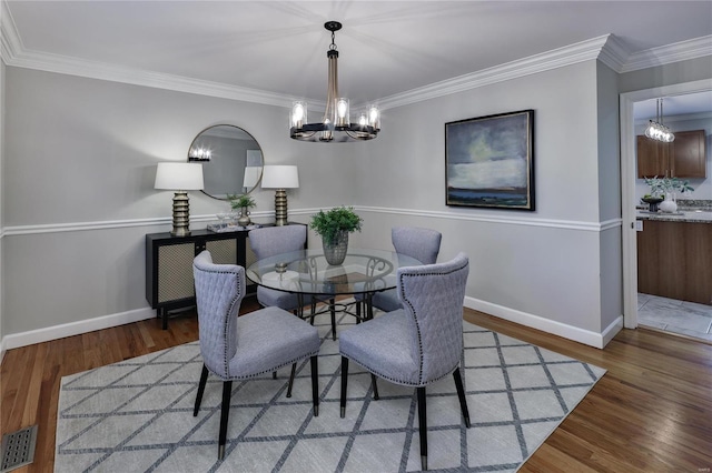 dining room featuring an inviting chandelier, dark hardwood / wood-style flooring, and crown molding