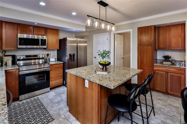 kitchen featuring a breakfast bar area, stainless steel appliances, a center island, light stone counters, and decorative light fixtures