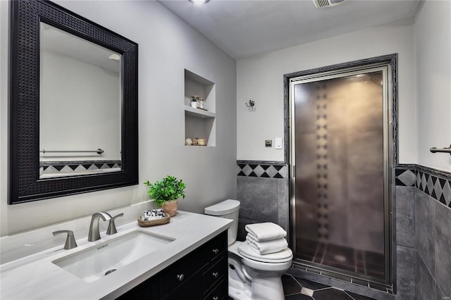 bathroom featuring built in features, vanity, toilet, and tile walls