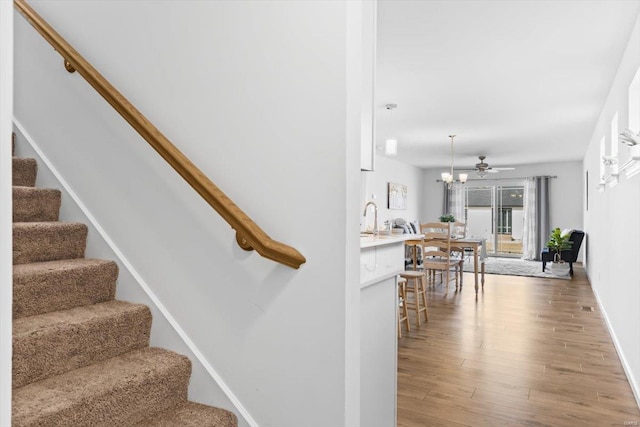 stairs with hardwood / wood-style flooring, sink, and ceiling fan