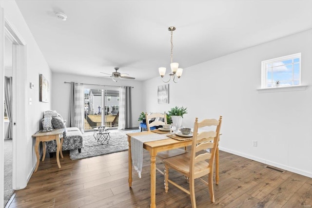 dining area featuring a healthy amount of sunlight, dark hardwood / wood-style flooring, and ceiling fan with notable chandelier