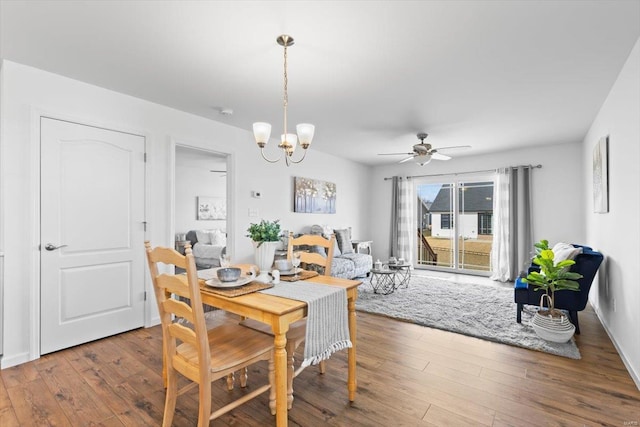 dining area with wood-type flooring and ceiling fan with notable chandelier