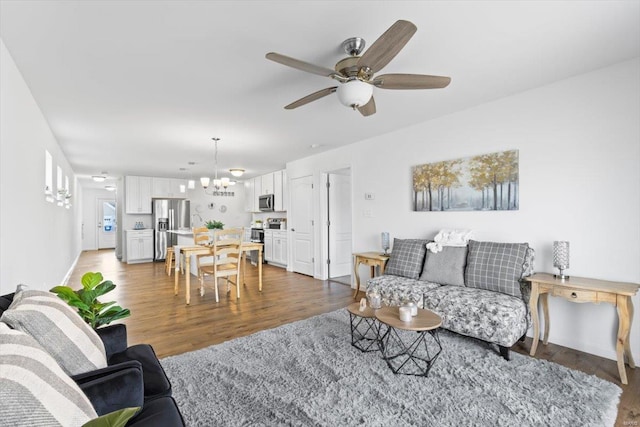 living room featuring ceiling fan with notable chandelier and wood-type flooring