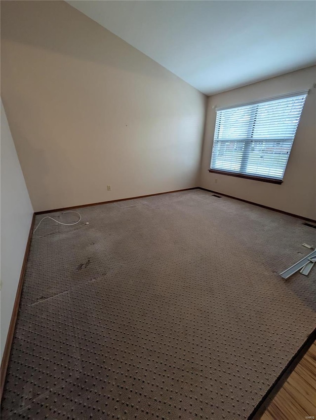 spare room featuring lofted ceiling and carpet flooring