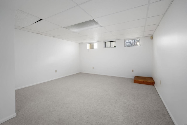 below grade area featuring a drop ceiling, baseboards, and carpet