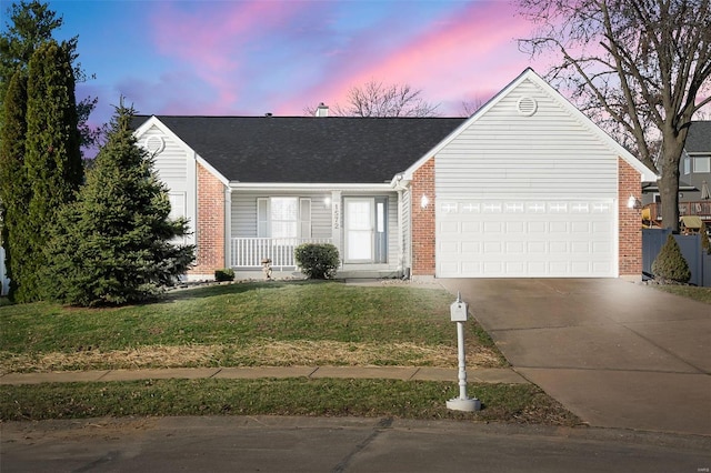 view of front of house with concrete driveway, a yard, brick siding, and a garage