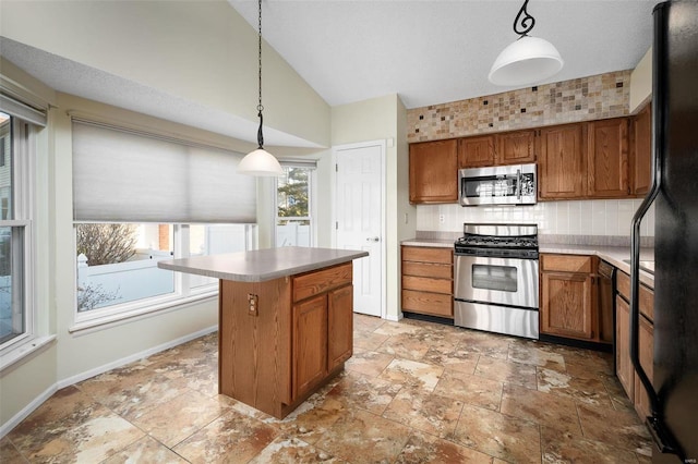 kitchen featuring a center island, lofted ceiling, decorative backsplash, brown cabinets, and stainless steel appliances