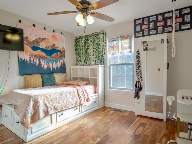 bedroom featuring baseboards, wood finished floors, visible vents, and ceiling fan