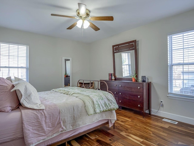 bedroom with visible vents, a ceiling fan, baseboards, and wood finished floors