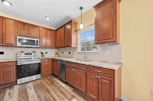 kitchen featuring appliances with stainless steel finishes, dark hardwood / wood-style floors, sink, hanging light fixtures, and light stone counters