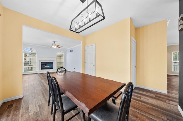 dining area with ornamental molding, a healthy amount of sunlight, and dark wood-type flooring