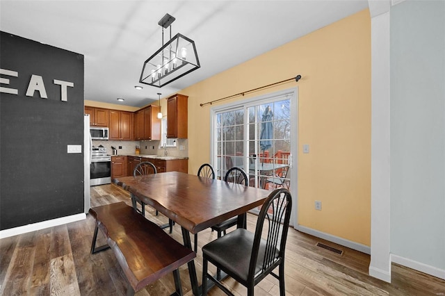 dining space featuring sink, light hardwood / wood-style flooring, and a chandelier