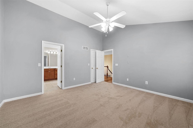 unfurnished bedroom with ceiling fan, connected bathroom, light carpet, and high vaulted ceiling