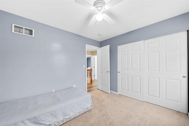 unfurnished bedroom featuring light carpet, ceiling fan, and a closet