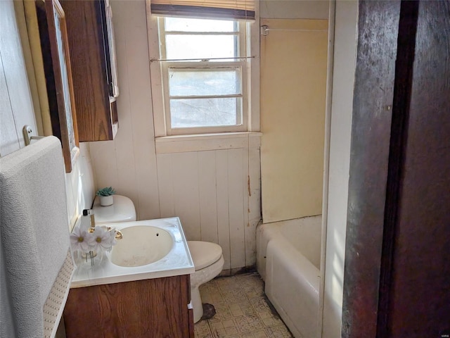 bathroom featuring vanity, wood walls, and toilet