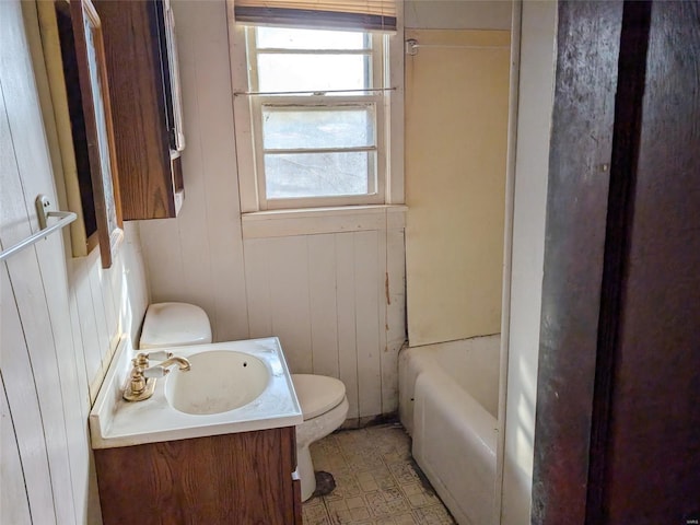 bathroom featuring vanity, a bathing tub, toilet, and wood walls