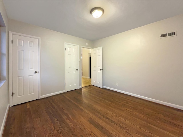 unfurnished bedroom with dark hardwood / wood-style flooring