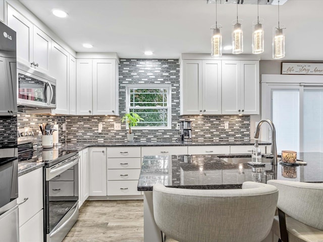 kitchen featuring white cabinetry, appliances with stainless steel finishes, and decorative light fixtures