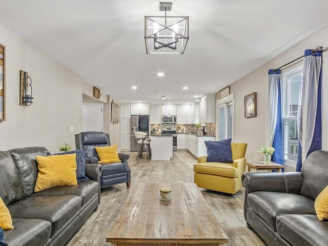 living room with a notable chandelier and light hardwood / wood-style flooring